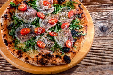 Pizza Italiana jambon, peynir, domates ve roka ile servis edilir..