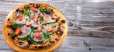 Pizza Italiana jambon, peynir, domates ve roka ile servis edilir..