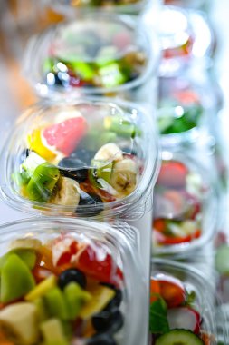 Önceden paketlenmiş meyve ve sebze salatalarıyla dolu plastik kutular ticari bir buzdolabında satılıyor.