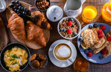 Breakfast served with coffee, orange juice, scrambled eggs, cereals, pancakes and croissants.