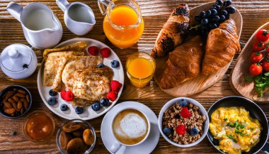Breakfast served with coffee, orange juice, scrambled eggs, cereals, pancakes and croissants.