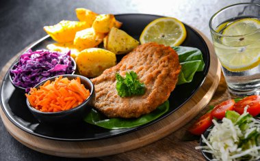 Patates ve sebze salatalı ekmek kırıntılarıyla kaplı domuz pirzolası.