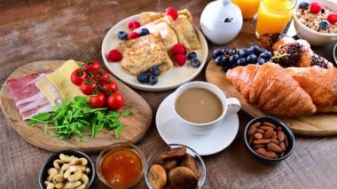 Breakfast served with coffee, orange juice, scrambled eggs, cereals, pancakes and croissants.