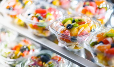 Plastic boxes with pre-packaged fruit salads, put up for sale in a commercial refrigerator