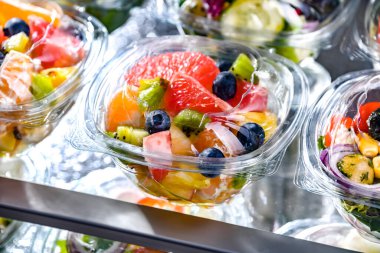 Plastic boxes with pre-packaged fruit salads, put up for sale in a commercial refrigerator