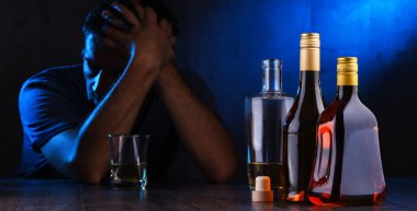 Alkol dolu şişeler ve sarhoş bir adam figürü.