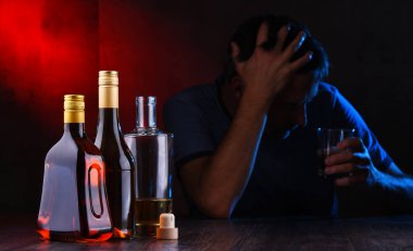 Alkol dolu şişeler ve sarhoş bir adam figürü.