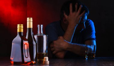 Alkol dolu şişeler ve sarhoş bir adam figürü.