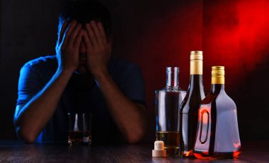 Alkol dolu şişeler ve sarhoş bir adam figürü.