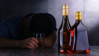 Alkol dolu şişeler ve sarhoş bir adam figürü.