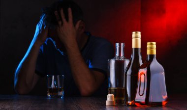 Alkol dolu şişeler ve sarhoş bir adam figürü.