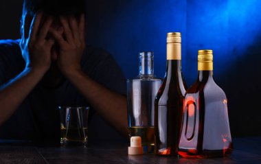 Alkol dolu şişeler ve sarhoş bir adam figürü.