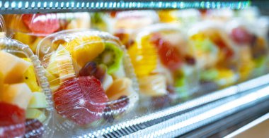 Ticari bir buzdolabında taze meyve sergilenen plastik kutular. Meyve salatası.