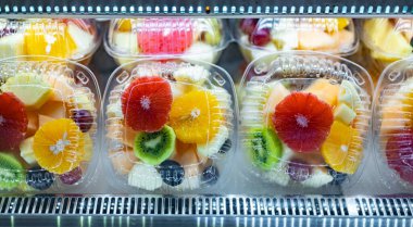 Ticari bir buzdolabında taze meyve sergilenen plastik kutular. Meyve salatası.