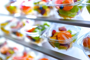 Plastic boxes with pre-packaged fruit salads, put up for sale in a commercial refrigerator