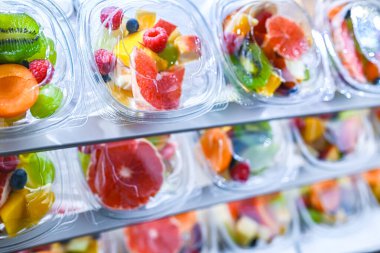 Plastic boxes with pre-packaged fruit salads, put up for sale in a commercial refrigerator