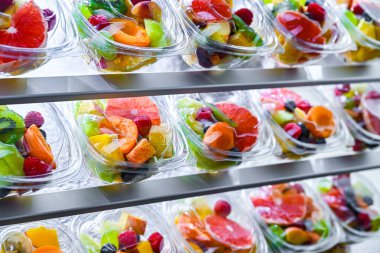 Plastic boxes with pre-packaged fruit salads, put up for sale in a commercial refrigerator