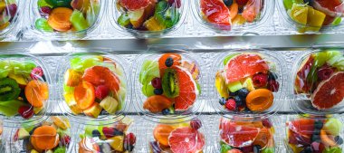 Plastic boxes with pre-packaged fruit salads, put up for sale in a commercial refrigerator