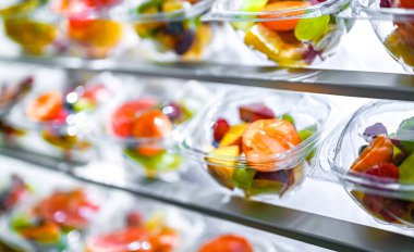 Plastic boxes with pre-packaged fruit salads, put up for sale in a commercial refrigerator