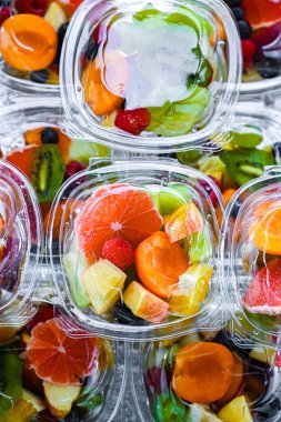 Plastic boxes with pre-packaged fruit salads, put up for sale in a commercial refrigerator