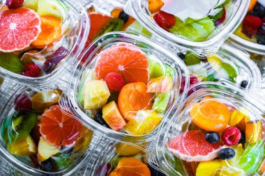 Plastic boxes with pre-packaged fruit salads, put up for sale in a commercial refrigerator