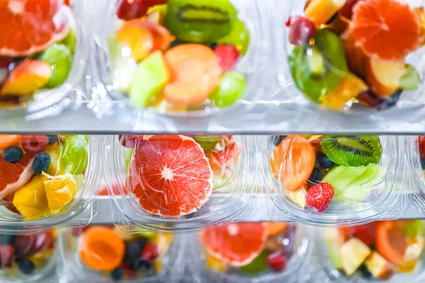 Plastic boxes with pre-packaged fruit salads, put up for sale in a commercial refrigerator