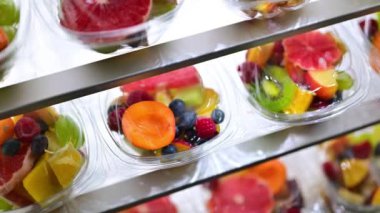 Plastic boxes with pre-packaged fruit salads, put up for sale in a commercial refrigerator