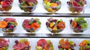 Plastic boxes with pre-packaged fruit salads, put up for sale in a commercial refrigerator