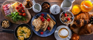 Breakfast served with coffee, orange juice, scrambled eggs, cereals, pancakes and croissants.