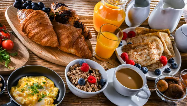 Breakfast served with coffee, orange juice, scrambled eggs, cereals, pancakes and croissants.