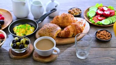 Kahvaltının yanında kahve, portakal suyu, kruvasan, mısır gevreği, çırpılmış yumurta ve krep var.