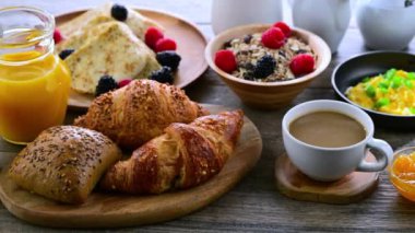 Kahvaltının yanında kahve, portakal suyu, kruvasan, mısır gevreği, çırpılmış yumurta ve krep var.