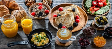 Kahvaltının yanında kahve, portakal suyu, kruvasan, mısır gevreği, çırpılmış yumurta ve krep var..