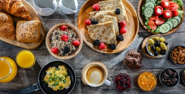 Kahvaltının yanında kahve, portakal suyu, kruvasan, mısır gevreği, çırpılmış yumurta ve krep var..