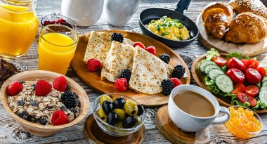 Kahvaltının yanında kahve, portakal suyu, kruvasan, mısır gevreği, çırpılmış yumurta ve krep var..