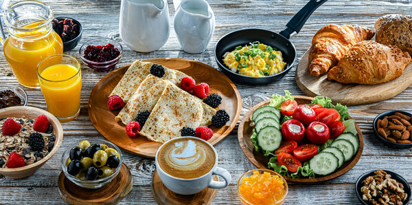 Breakfast served with coffee, orange juice, croissants, cereals, scrambled eggs and pancakes.