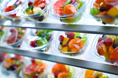 Plastic boxes with pre-packaged fruit salads, put up for sale in a commercial refrigerator