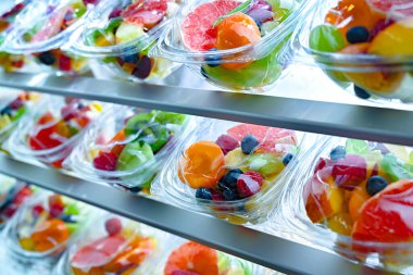 Plastic boxes with pre-packaged fruit salads, put up for sale in a commercial refrigerator