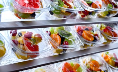 Plastic boxes with pre-packaged fruit salads, put up for sale in a commercial refrigerator