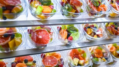 Plastic boxes with pre-packaged fruit salads, put up for sale in a commercial refrigerator