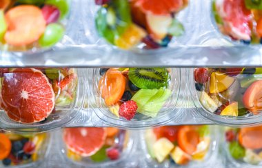 Plastic boxes with pre-packaged fruit salads, put up for sale in a commercial refrigerator