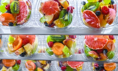 Plastic boxes with pre-packaged fruit salads, put up for sale in a commercial refrigerator