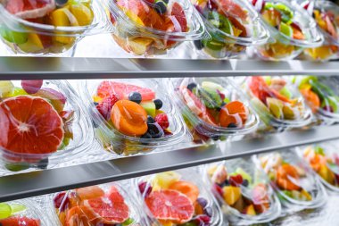 Plastic boxes with pre-packaged fruit salads, put up for sale in a commercial refrigerator