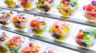 Plastic boxes with pre-packaged fruit salads, put up for sale in a commercial refrigerator