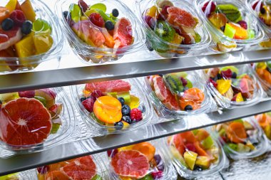 Plastic boxes with pre-packaged fruit salads, put up for sale in a commercial refrigerator