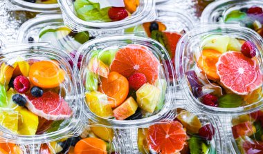 Plastic boxes with pre-packaged fruit salads, put up for sale in a commercial refrigerator
