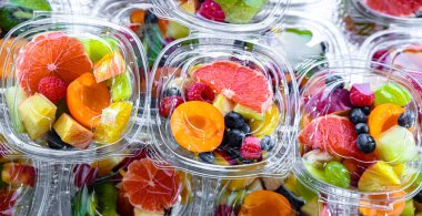 Plastic boxes with pre-packaged fruit salads, put up for sale in a commercial refrigerator