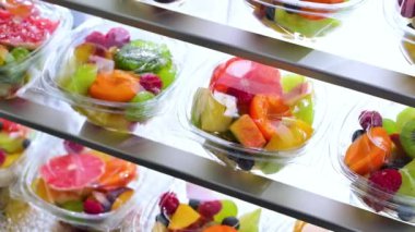 Plastic boxes with pre-packaged fruit salads, put up for sale in a commercial refrigerator