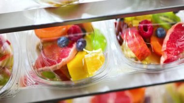 Plastic boxes with pre-packaged fruit salads, put up for sale in a commercial refrigerator