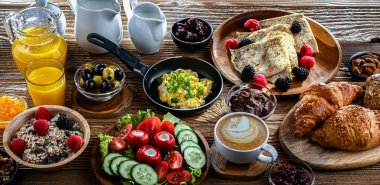 Kahvaltının yanında kahve, portakal suyu, kruvasan, mısır gevreği, çırpılmış yumurta ve krep var..